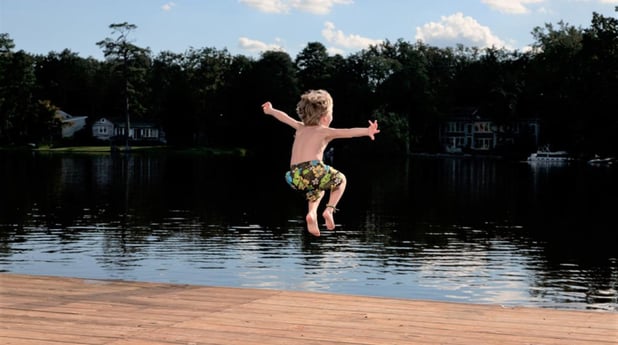 Boy jumping in lake istock